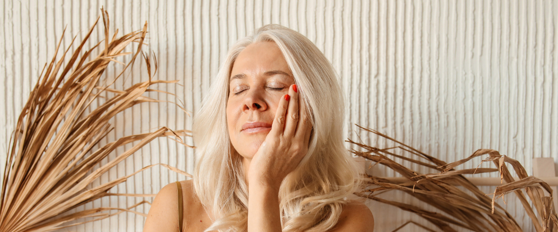 mature woman with a beautiful, plump and smooth skin touching her face with one hand