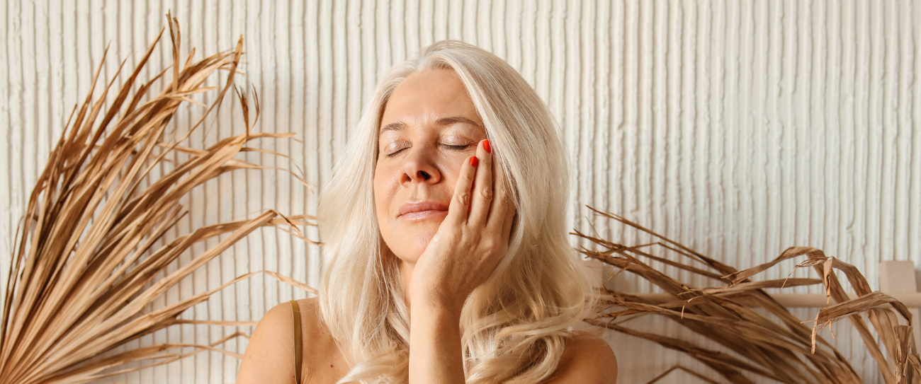 mature woman with a beautiful, plump and smooth skin touching her face with one hand